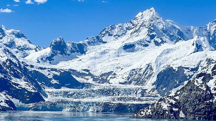 A scenic view of an Alaskan glacier and a small boat in the water.